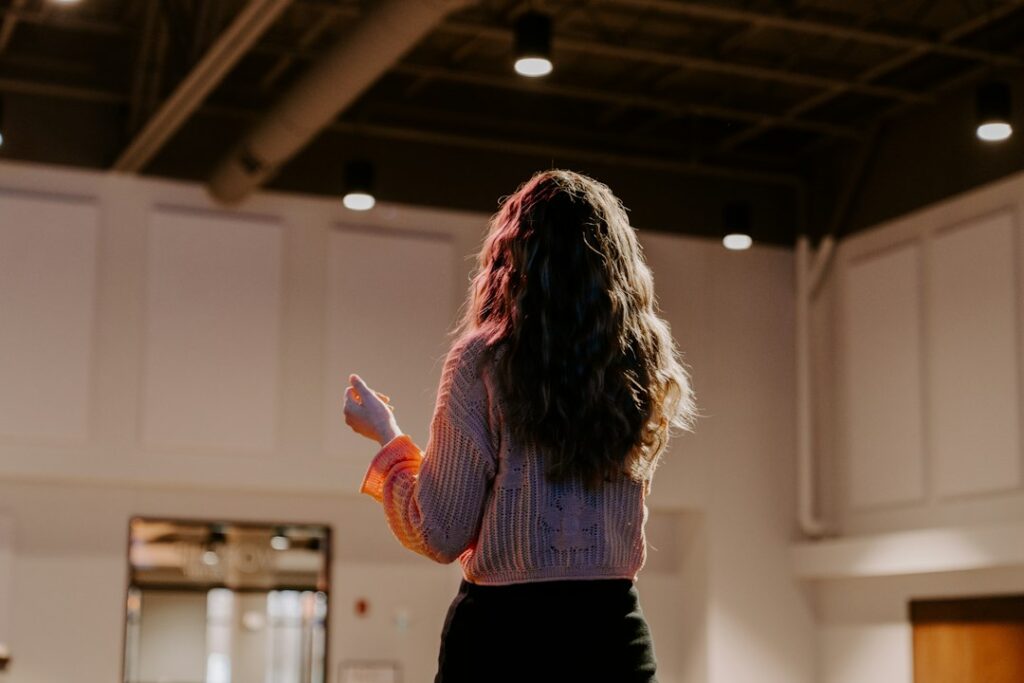 A person rehearsing alone in an empty room under warm lights, the last step in how to make a good PowerPoint presentation
