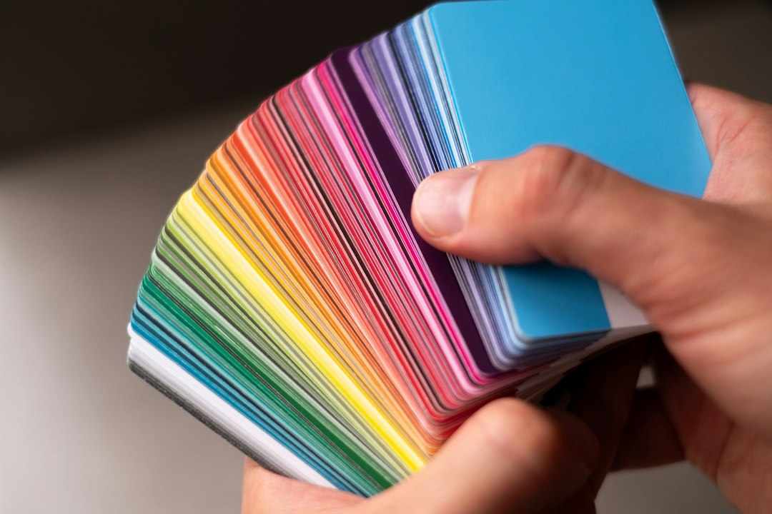 A hand fanning out a rainbow of color swatch cards, choosing a palette the way you would pick theme colors in Google Slides