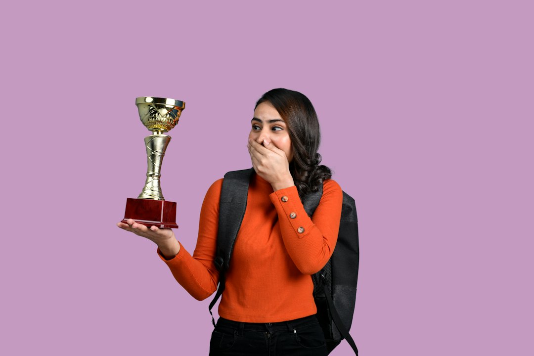 Woman holding a small gold trophy with a surprised smile, a fun award for the winner of a PowerPoint night