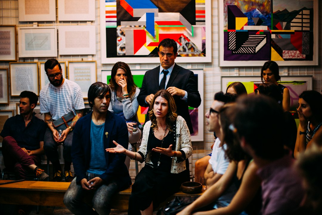 A woman speaking with an open-hand gesture to a small seated group, presenting one of her presentation topics